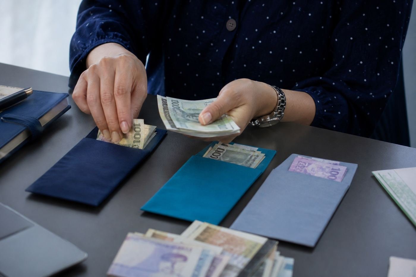 Hands sorting monthly cash into small pouches for rent, food and loan payments